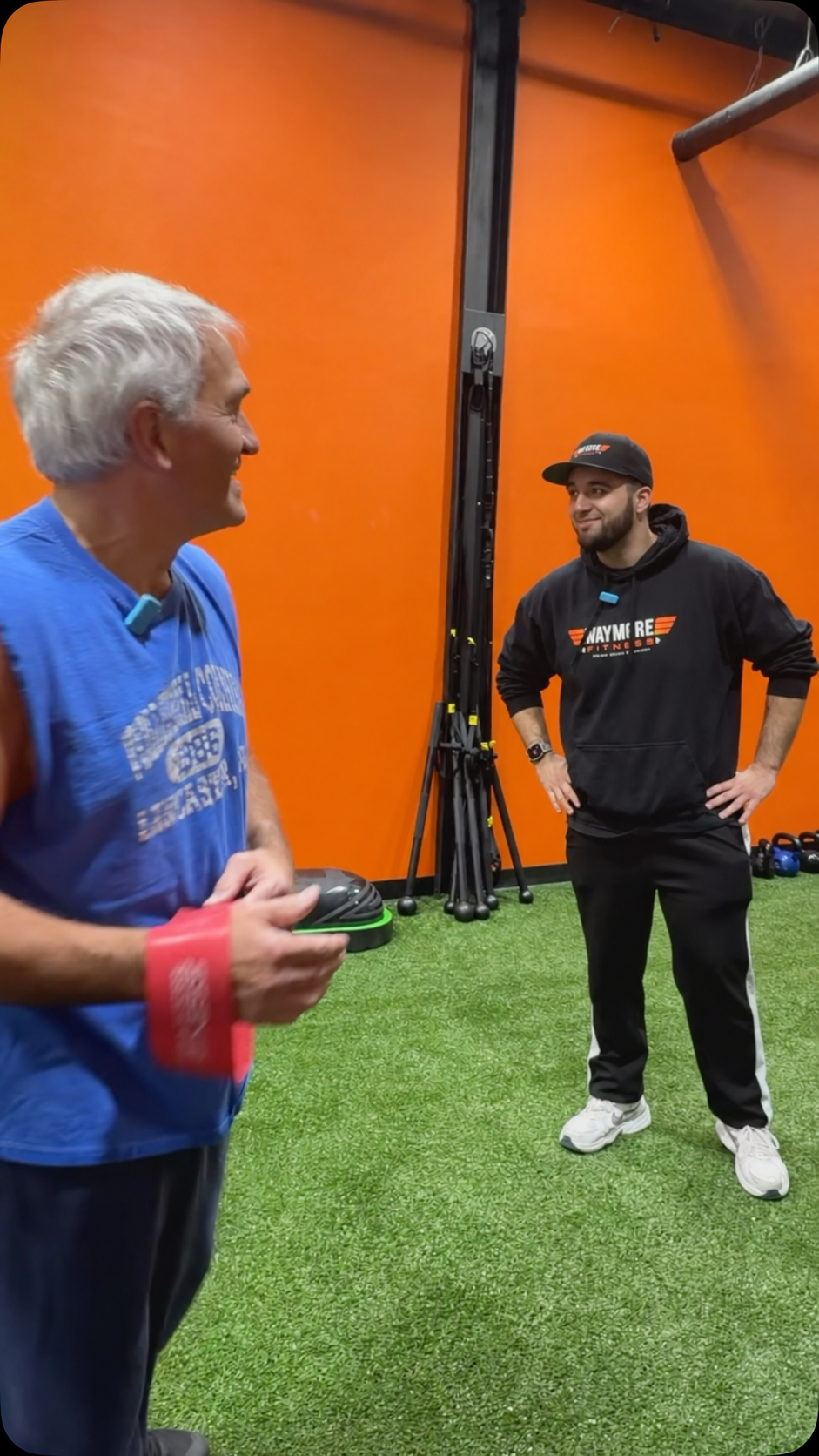 A WayMore member holding a resistance band with his coach on the gym floor