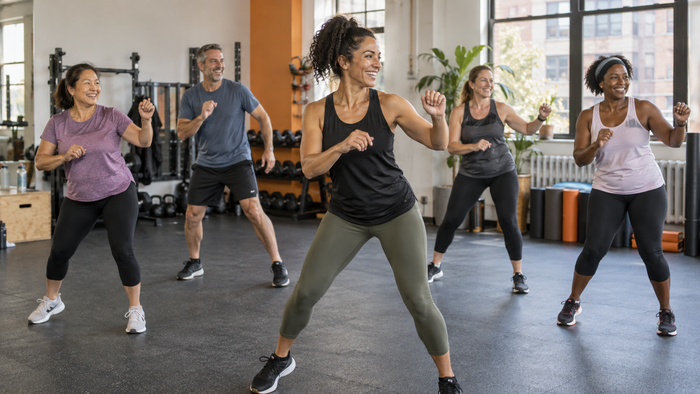 Illustrative fitness scene: adults following a dance fitness instructor
