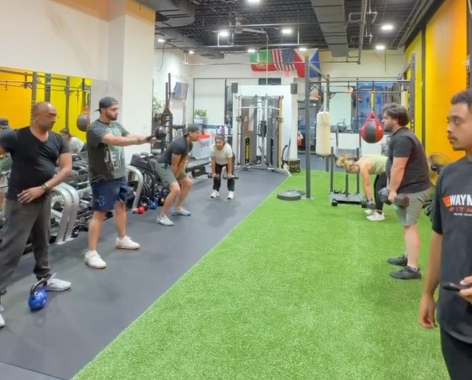 A new athlete pushing a sled in WayMore’s orange-wall gym — film-style campaign concept